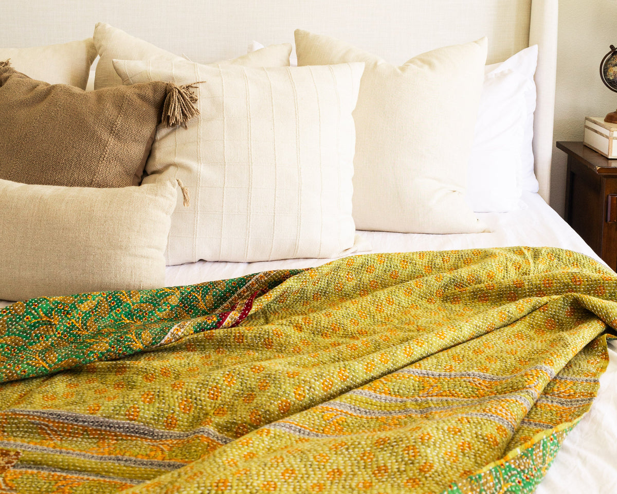A colorful kantha quilt laying across a bed