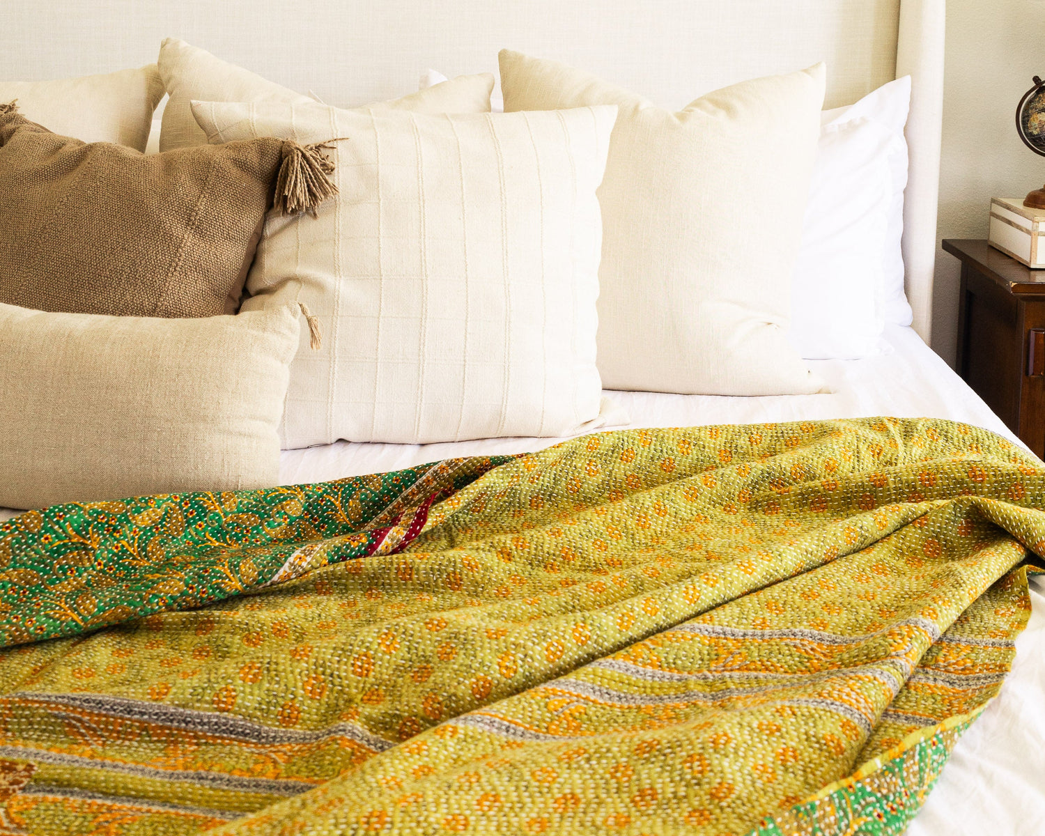A colorful kantha quilt laying across a bed